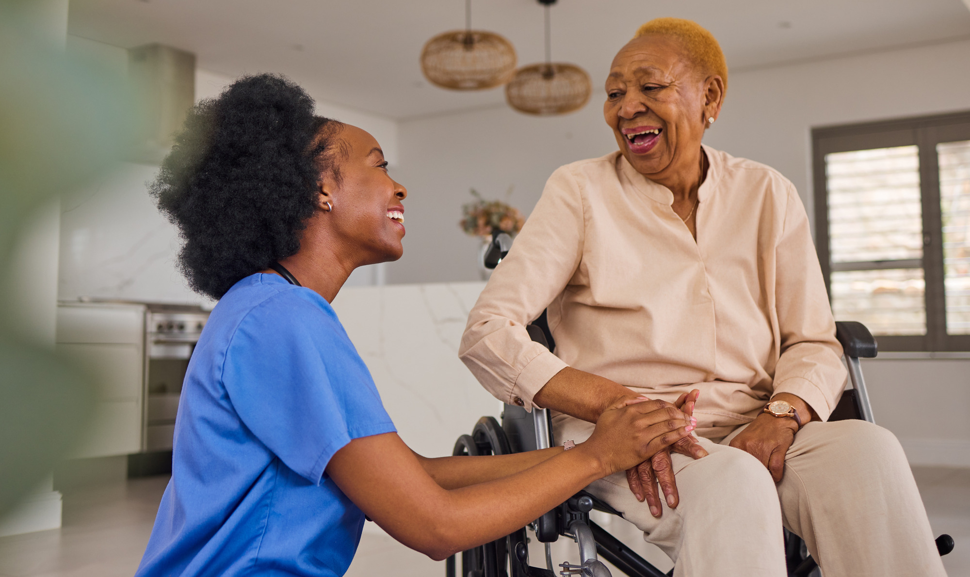 nurse kneeling next to her patient in her wheelchair